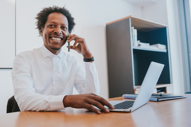 Professioneller Geschäftsmann, der während der Arbeit in seinem modernen Büro telefoniert. Geschäftskonzept.