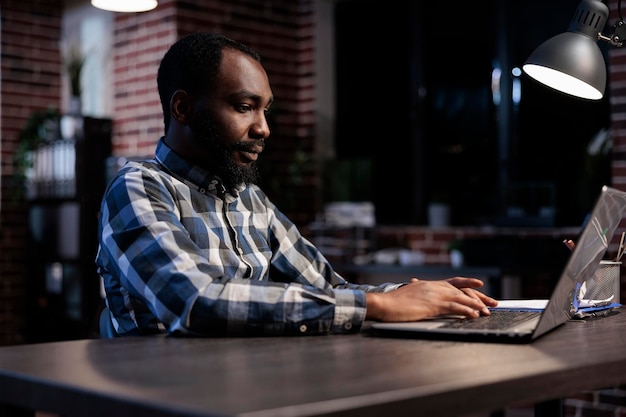 Professioneller Handelsagent für die Forex-Börse, der Finanzdiagramme und Anlagegewinne in Echtzeit verfolgt. Afroamerikanischer Unternehmensinvestor, der nachts am Schreibtisch im Büroarbeitsplatz sitzt.