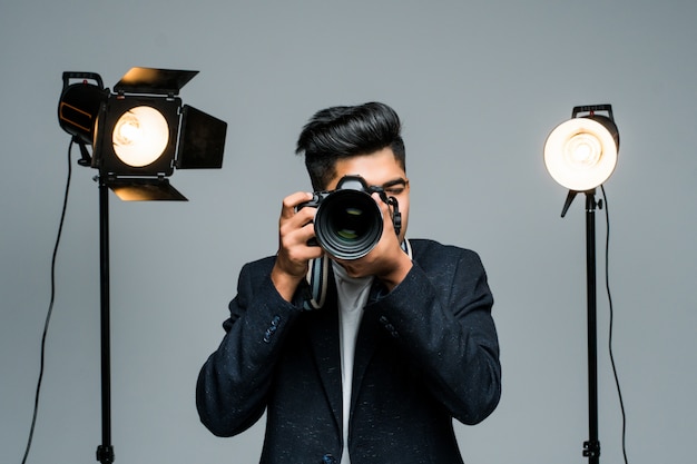 Professioneller indischer junger Fotograf, der Fotos im Studio mit Leight macht