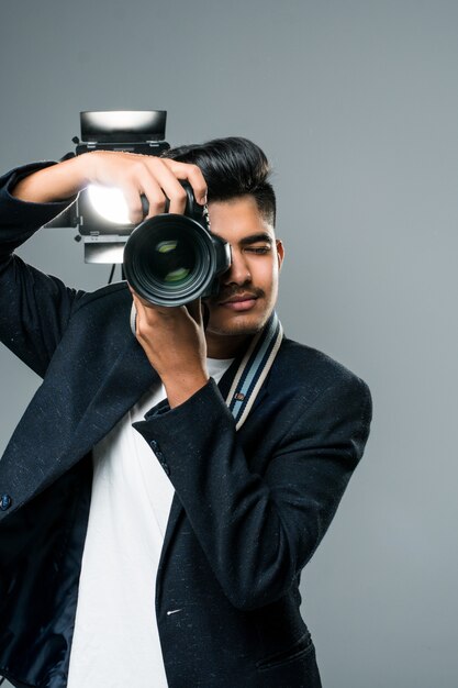 Professioneller indischer junger Fotograf, der Fotos im Studio mit Leight macht