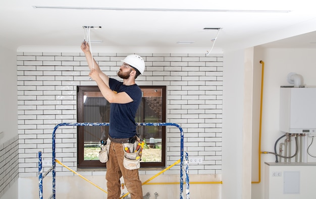 Professioneller Overall mit Werkzeugen im Hintergrund der Reparaturstelle. Hausrenovierungskonzept.