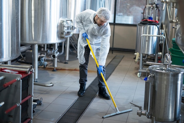 Professioneller Reiniger trägt Schutz einheitlichen Reinigungsboden der Produktionsanlage