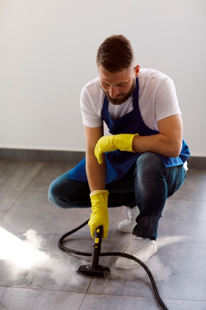 Kostenloses Foto professioneller reinigungsdienstmitarbeiter, der im büro einen dampfreiniger verwendet