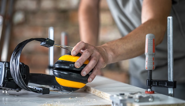 Professioneller Tischlerarbeitsplatz mit Schutzkopfhörern, persönlicher Schutz für die Arbeit in der Holzwerkstätte.