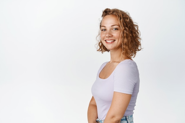 Profilaufnahme eines aufrichtigen blonden Mädchens, das glücklich lächelt und schaut und im T-Shirt weiß steht. Platz kopieren