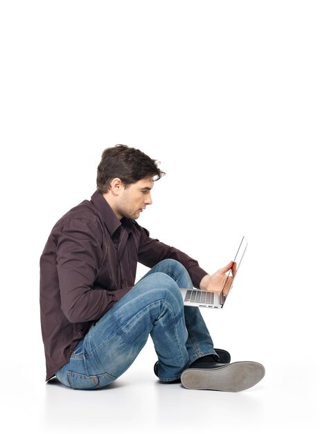 Profilporträt des glücklichen Mannes, der am Laptop in den auf Weiß lokalisierten Casuals arbeitet.
