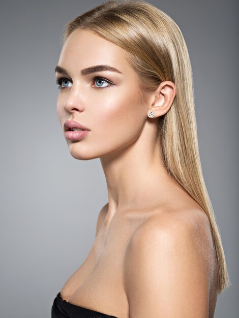 Profilporträt einer schönen jungen Frau mit langen hellen glatten Haaren.