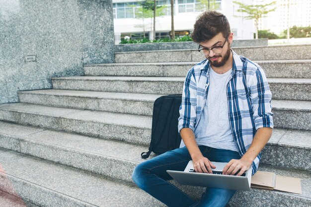 Programmierer, der an Computer auf Marmortreppe in der Straße arbeitet