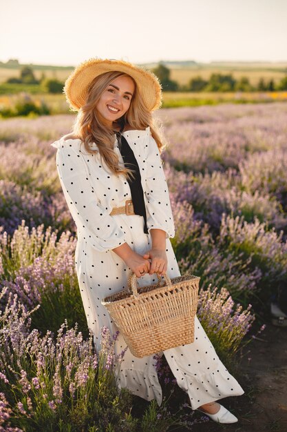 Provence Frau, die im Lavendelfeld entspannt. Dame in einem weißen Kleid. Mädchen mit einem Strohhut und einem Korb.