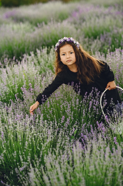 Provence Kind, das im Lavendelfeld entspannt. Kleine Dame in einem schwarzen Kleid. Mädchen mit Tasche.