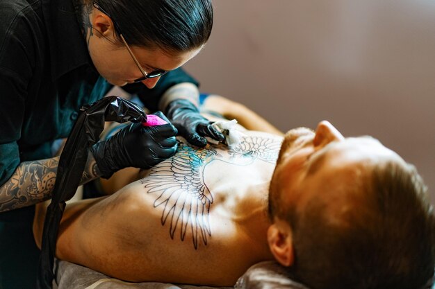 Prozess des Tattoo-Salons. Ein Tattoo-Girl stopfte ein Tattoo. der Prozess, ein Tattoo auf den Körper zu stopfen. Hände aus nächster Nähe.