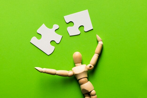 Puzzleteil mit hölzerner menschlicher Figur auf grünem Hintergrund