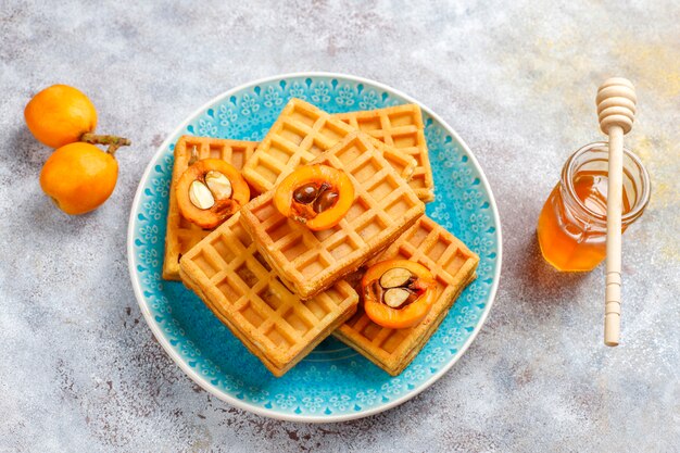 Quadratische belgische Waffeln mit Wollmispelfrüchten und Honig.