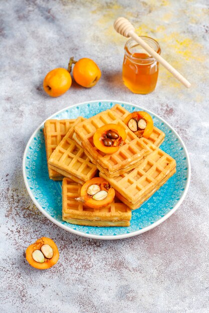 Quadratische belgische Waffeln mit Wollmispelfrüchten und Honig.