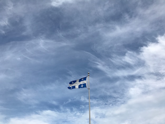 Quebec Flagge unter den schönen Wolken am Himmel