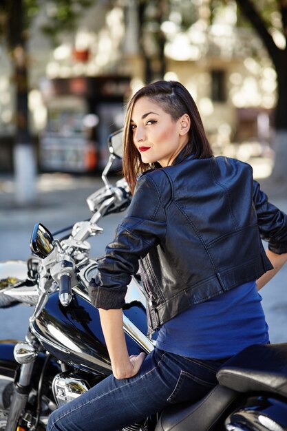 Radfahrermädchen in einer Lederjacke auf einem Motorrad