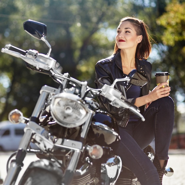 Radfahrermädchen in einer Lederjacke auf einem Motorrad