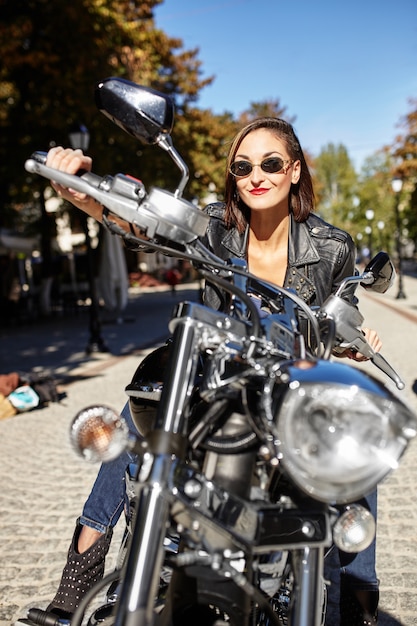 Radfahrermädchen in einer Lederjacke auf einem Motorrad