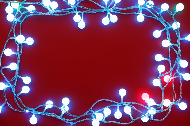 Rahmen aus weihnachtslichtern, die auf rotem hintergrund leuchten
