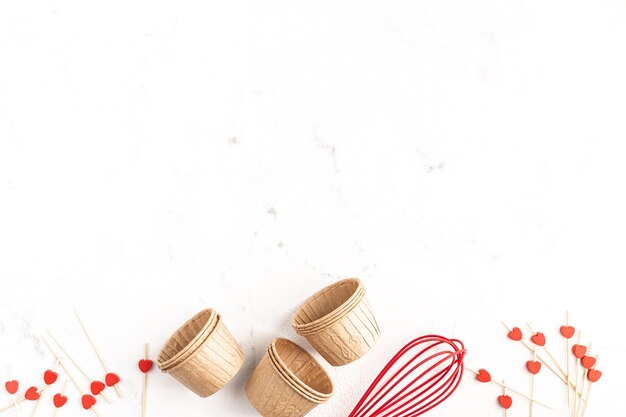 Rahmen für Hausbacken auf weißem Hintergrund. Cupcake-Formen aus Papier. Schachteln mit einem roten Band zum Valentinstag. Platz kopieren.