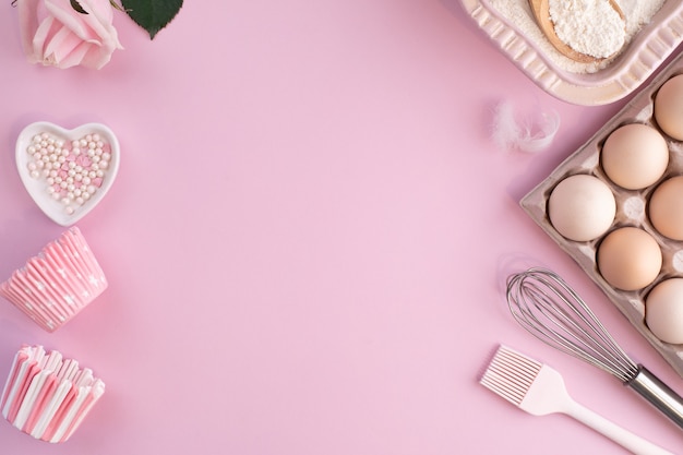 Rahmen von Lebensmittelzutaten zum Backen auf einem sanft rosa Pastellhintergrund. Koch flach lag mit Kopierraum. Draufsicht. Backkonzept. flach liegen