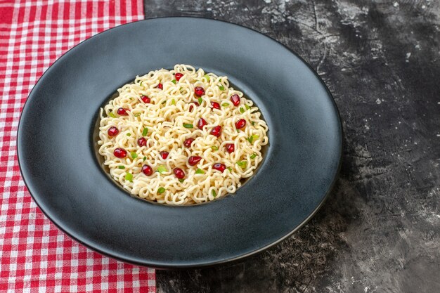 Ramen-Nudeln von unten auf dunklem runden Teller rot-weiß karierte Tischdecke auf dunklem Tisch