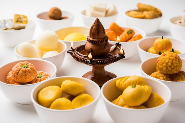 Rangoli mit verschiedenen indischen süßigkeiten oder mithai in einer schüssel für diwali oder andere feste, selektiver fokus