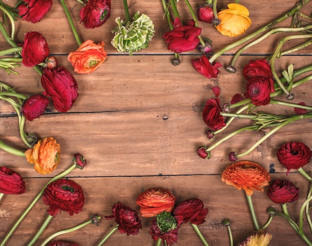 Ranunkulyus-Blumenstrauß von roten Blumen auf einem Holztisch