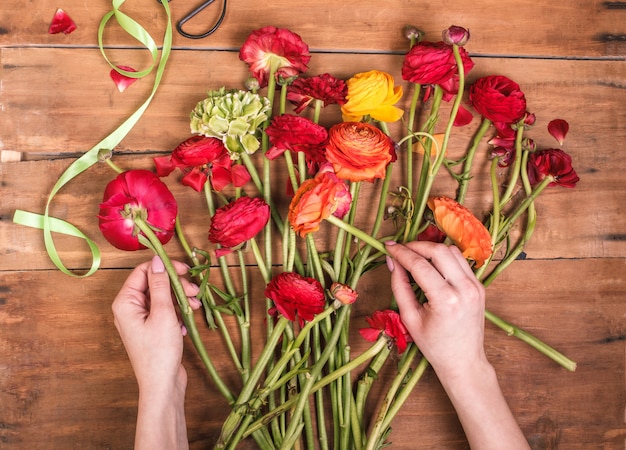 Kostenloses Foto ranunkulyus strauß roter blumen auf holz