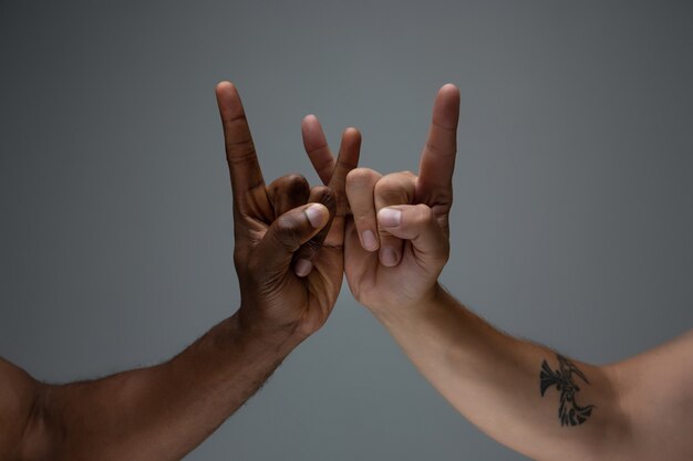 Rassentoleranz. Respektiere die soziale Einheit. Afrikanische und kaukasische Hände, die lokal auf grau gestikulieren