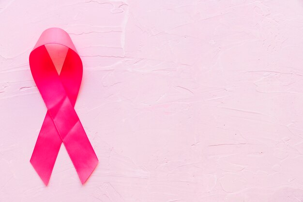 Realistisches rosa Band, das Brustkrebsbewusstseinssymbol auf rosa Stein zeigt