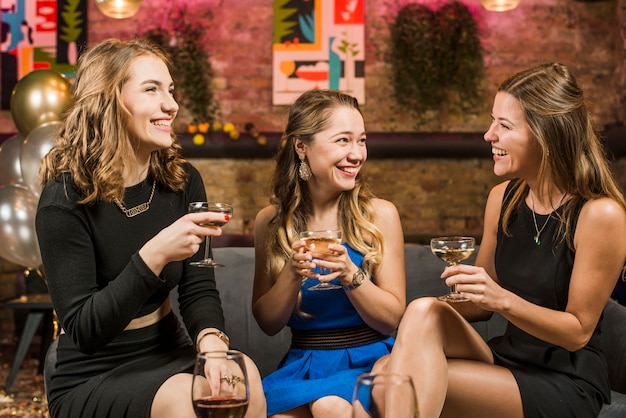 Recht junge Freundinnen in der Bar Getränke genießend