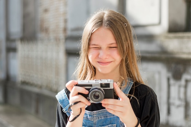 Kostenloses Foto recht nettes junges mädchen, das retro- kamera hält