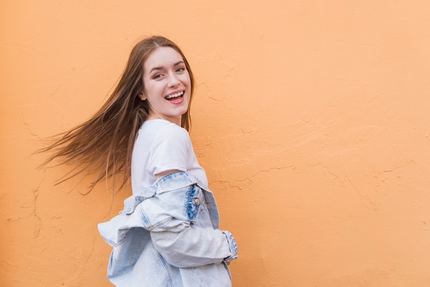 Kostenloses Foto recht schöne junge frau, die nahe farbigem wandhintergrund aufwirft