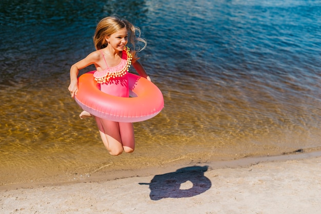 Kostenloses Foto recht sorgloses mädchen im badeanzug, der auf küste springt