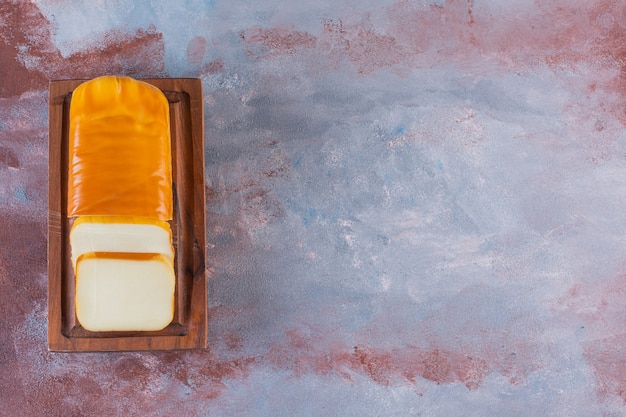 Rechteckig geschnittener Käse auf einem Brett auf der Marmoroberfläche