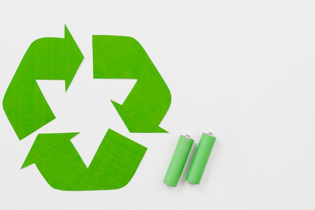 Recycling-Symbol neben grünen Batterien