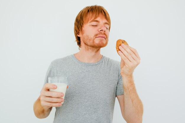 Red-haired Mann mit Glas Milch Riechen Cookie