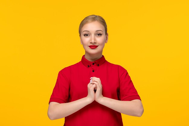 Red Shirt Day süßes Mädchen, das Hände zusammenhält und in einem roten Hemd auf gelbem Hintergrund lächelt
