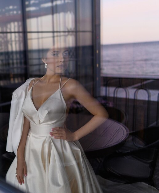 Reflexion des Mädchens im Hochzeitskleid im Fenster