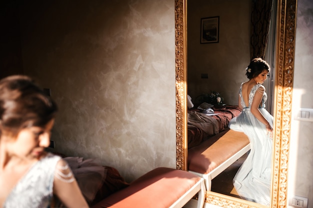 Reflexion einer Braut, die auf dem Bett vor einem Spiegel sitzt