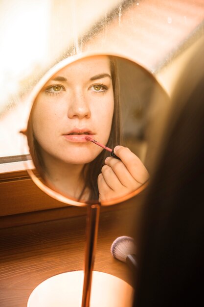 Reflexion einer Frau, die Lippenstift auf ihren Lippen anwendet