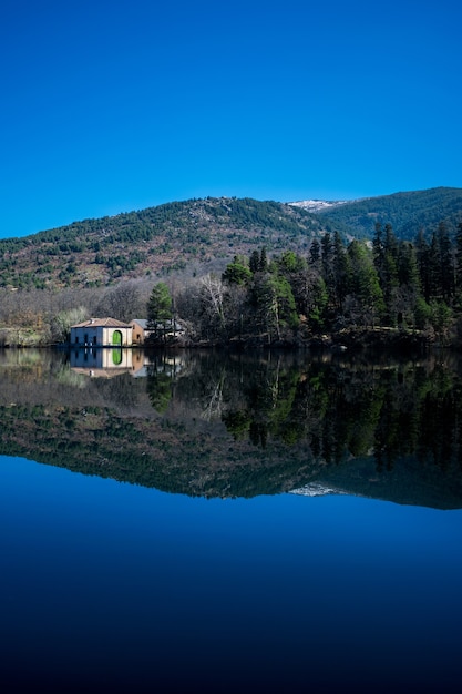 Reflexion von Bäumen und Hügeln auf einem See unter dem Sonnenlicht und einem blauen Himmel