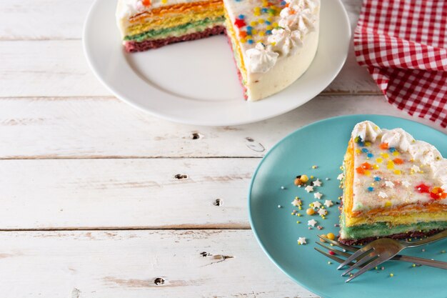 Regenbogen-Schichtkuchen auf weißem Holztisch