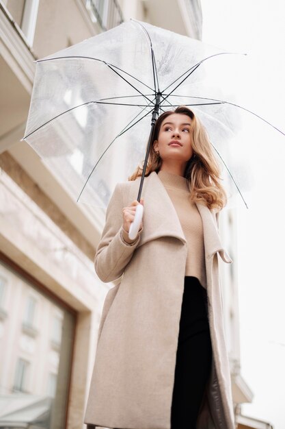 Regenporträt der jungen schönen Frau mit Regenschirm