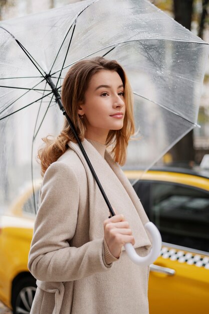 Regenporträt der jungen schönen Frau mit Regenschirm