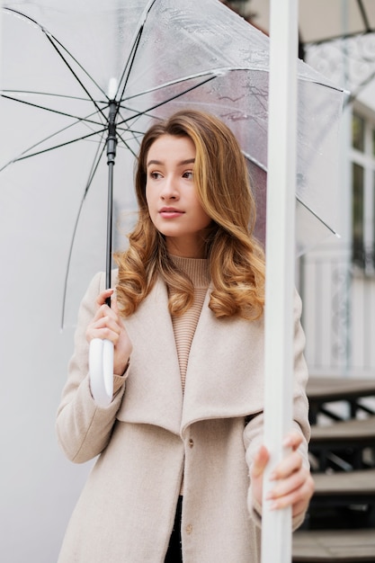 Regenporträt der jungen schönen Frau mit Regenschirm