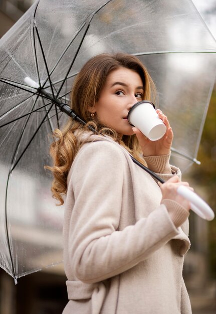Regenporträt der jungen schönen Frau mit Regenschirm