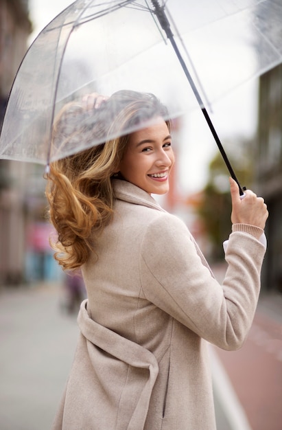 Kostenloses Foto regenporträt der jungen schönen frau mit regenschirm