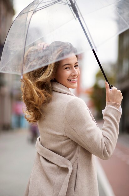 Regenporträt der jungen schönen Frau mit Regenschirm